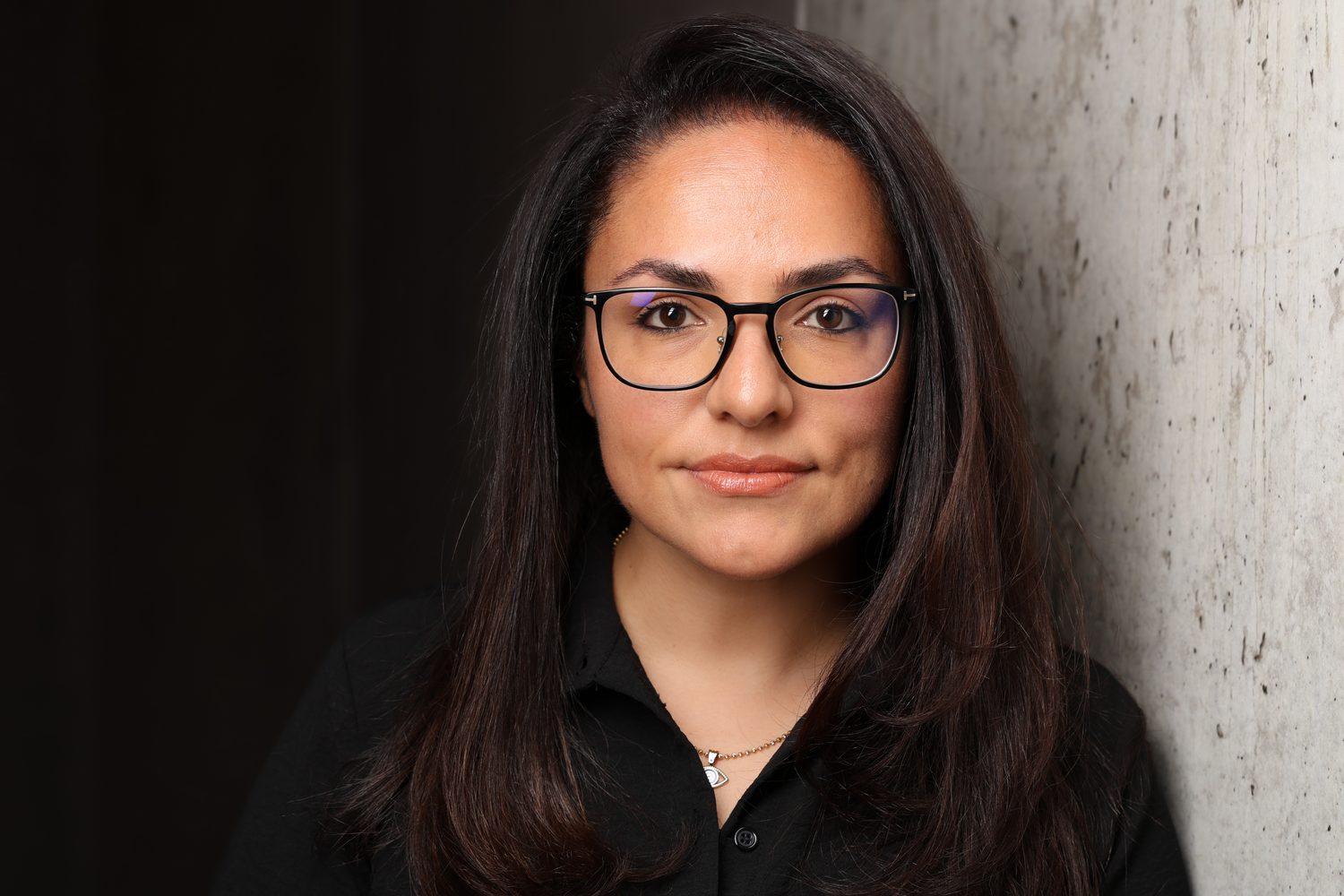 Portrait of Sanaz Hanke against a concrete wall